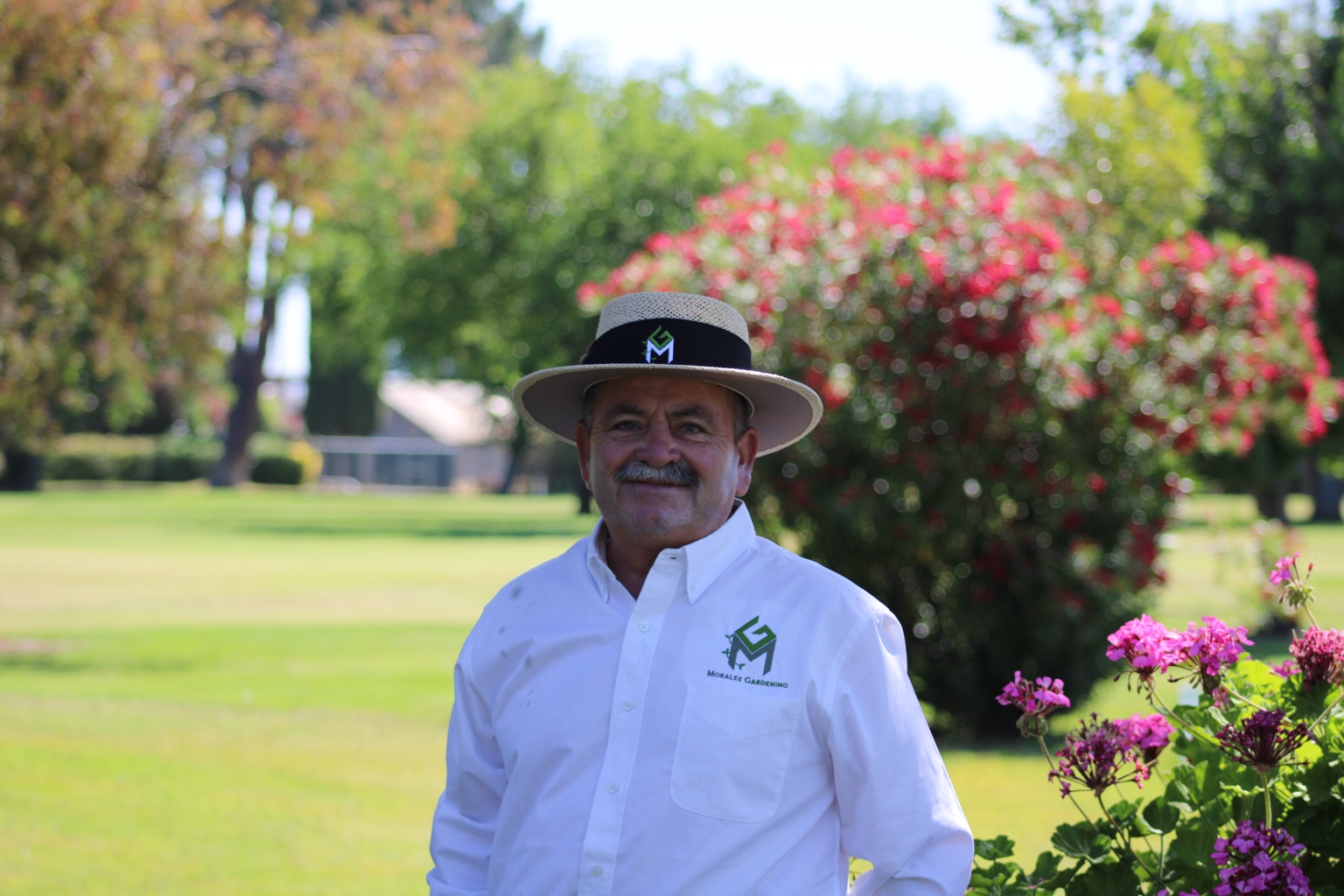 Fernando Morales Sr., Owner and Operations Manager, wearing a Morales Gardening shirt and hat in a garden